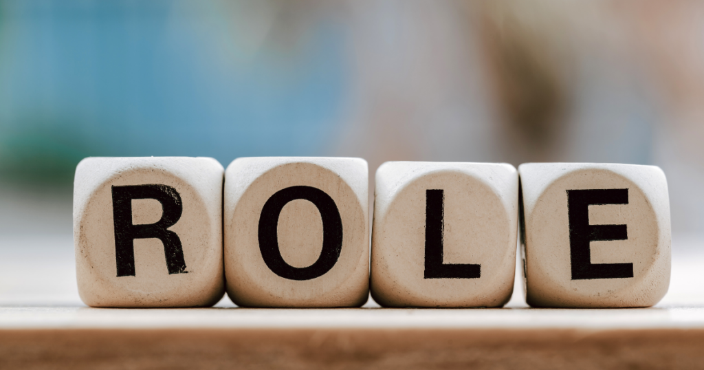 Four wooden letter blocks spell the word 'ROLE' on a light surface.