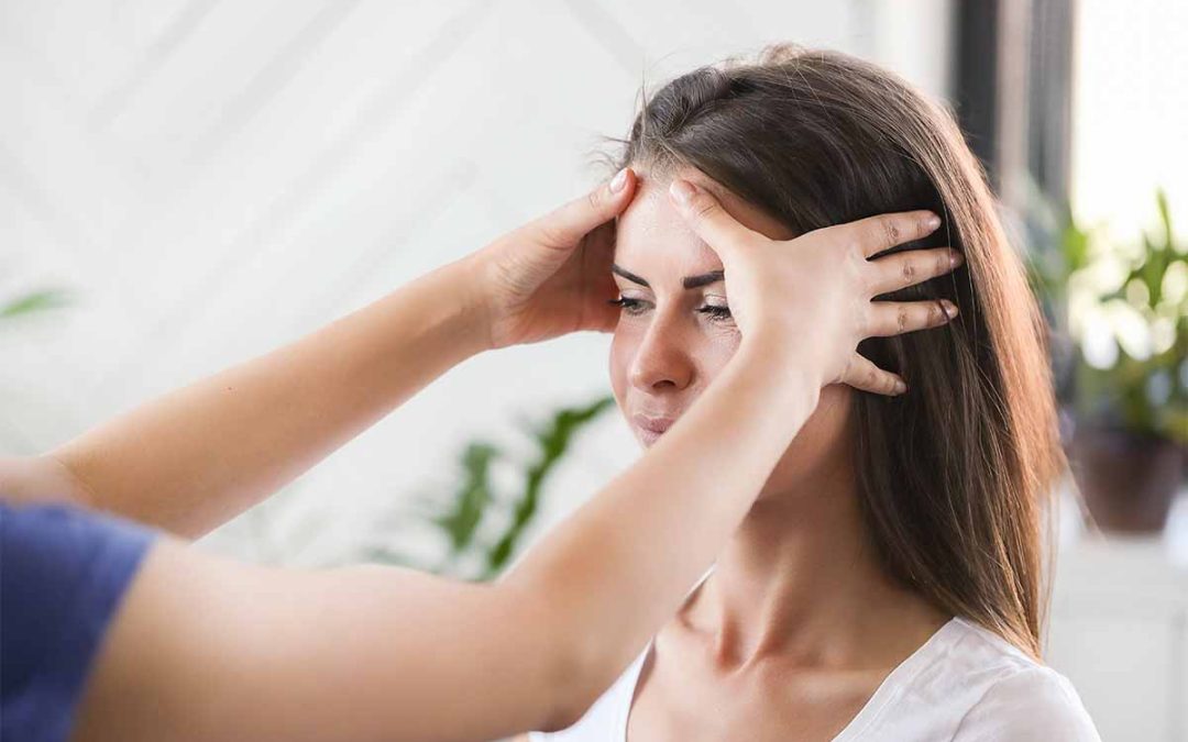 Woman receives temple pressure massage to relieve a headache relief session about stress.